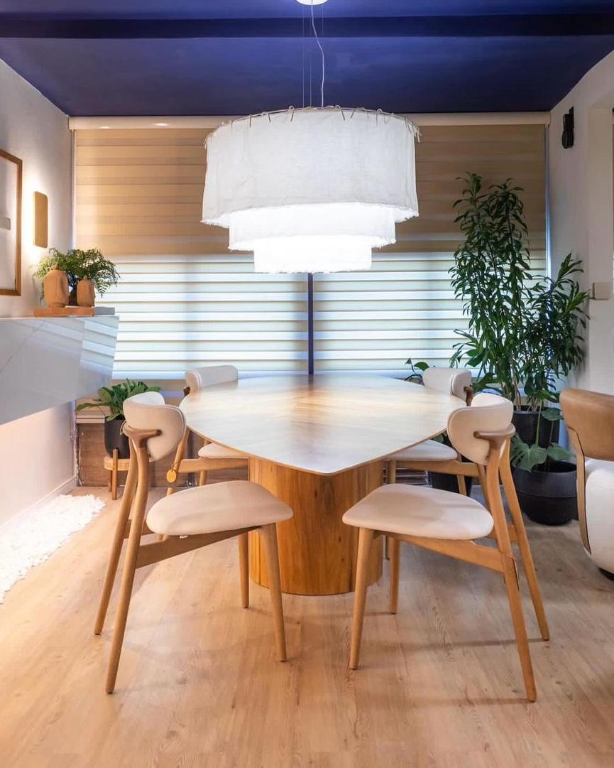 Sala de jantar com mesa redonda em madeira e cadeiras claras